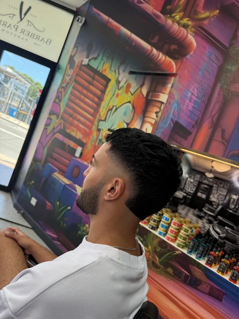 Taper fade with beard against the mural